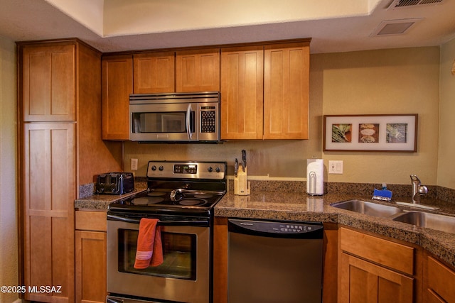 kitchen featuring a sink, tile counters, stainless steel appliances, and brown cabinets