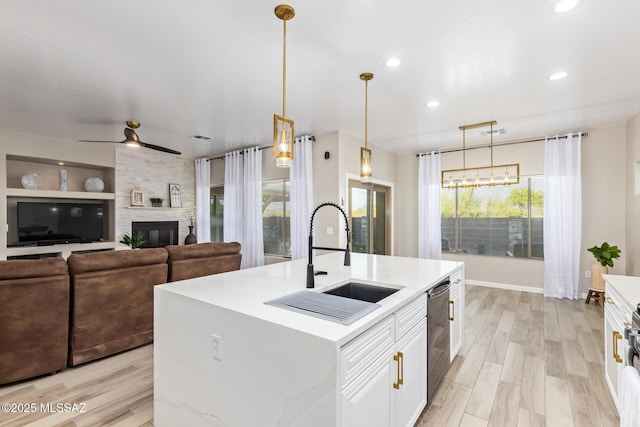 kitchen with white cabinets, a sink, light countertops, light wood-style flooring, and recessed lighting
