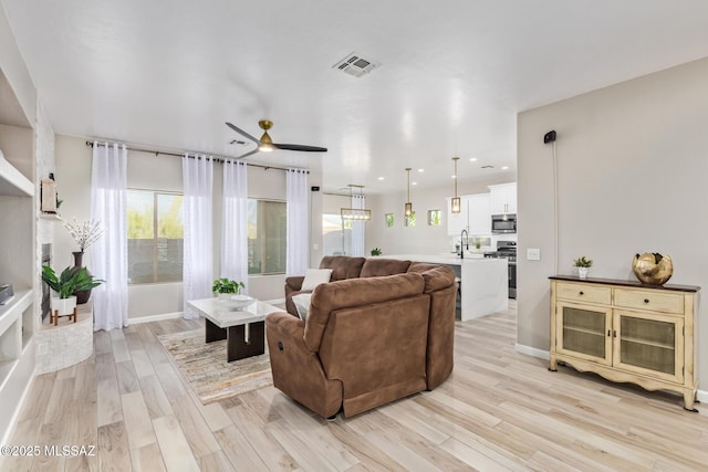 living room with light wood-style flooring, a ceiling fan, baseboards, recessed lighting, and visible vents