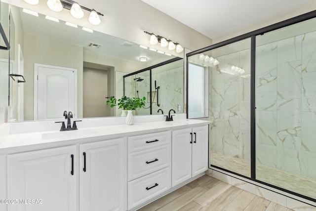 bathroom featuring a sink, a marble finish shower, double vanity, and visible vents