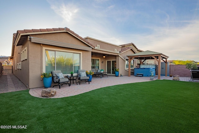 back of property with a ceiling fan, a lawn, a patio area, a hot tub, and a fenced backyard