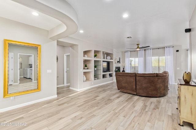 living room with independent washer and dryer, light wood-style floors, built in features, recessed lighting, and baseboards