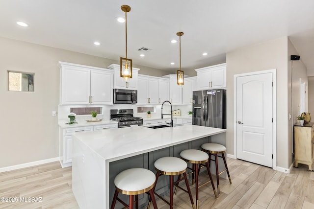 kitchen with light wood-style floors, a sink, white cabinets, and stainless steel appliances