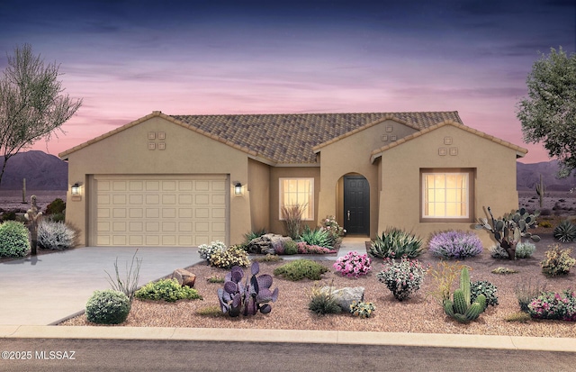 mediterranean / spanish house featuring a tiled roof, a garage, driveway, and stucco siding