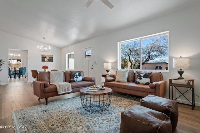 9453 E Pena Dr, Tucson, AZ 85730 - living room with ceiling fan with notable chandelier, lofted ceiling, wood finished floors, and a healthy amount of sunlight
