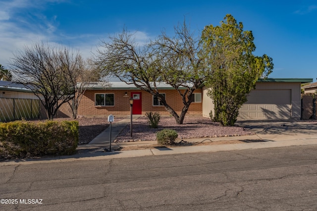 9453 E Pena Dr, Tucson, AZ 85730 - ranch-style house featuring fence, an attached garage, concrete driveway, and brick siding