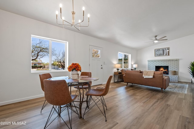 9453 E Pena Dr, Tucson, AZ 85730 - dining space featuring wood finished floors, a fireplace, baseboards, ceiling fan with notable chandelier, and vaulted ceiling