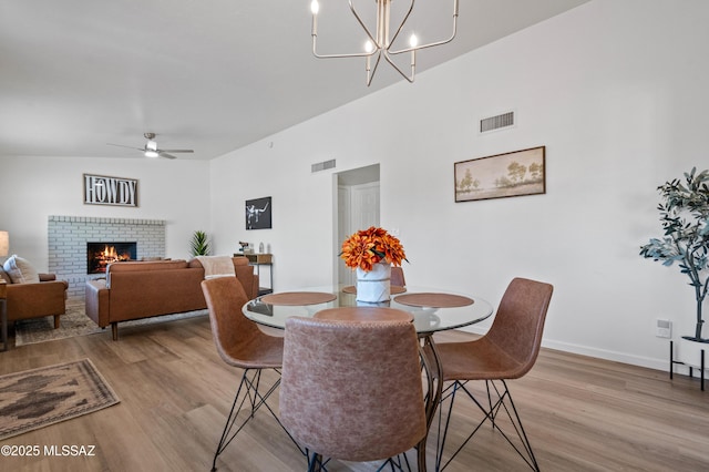 9453 E Pena Dr, Tucson, AZ 85730 - dining room with visible vents, light wood-style floors, ceiling fan with notable chandelier, and a fireplace