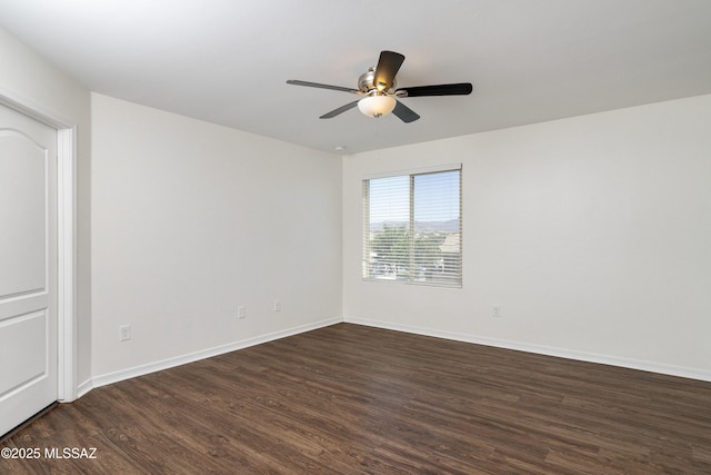 empty room with dark wood-style flooring, a ceiling fan, and baseboards