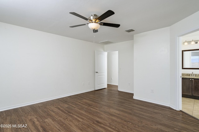 unfurnished room with wood finished floors, a sink, ceiling fan, and baseboards