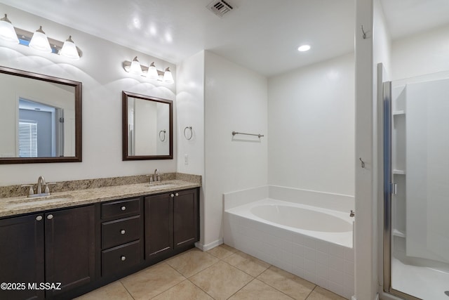 bathroom featuring tile patterned flooring, double vanity, a garden tub, and a stall shower