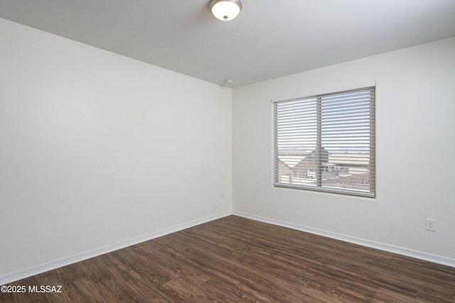 unfurnished room with dark wood-type flooring and baseboards
