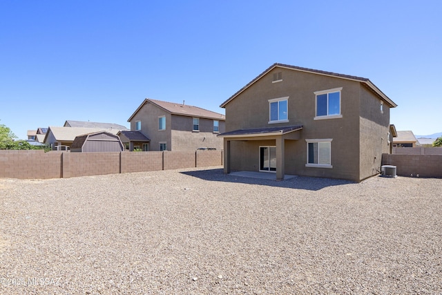rear view of house with cooling unit, a fenced backyard, stucco siding, and a patio