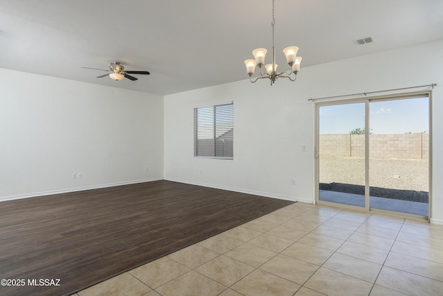 spare room with a chandelier, a ceiling fan, wood finished floors, and baseboards