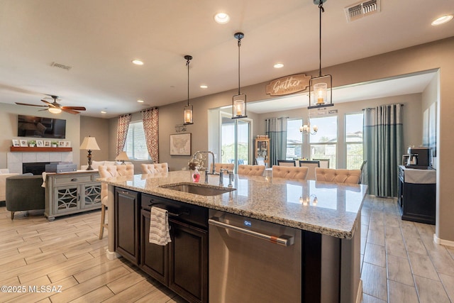 kitchen with stainless steel dishwasher, open floor plan, visible vents, and a sink