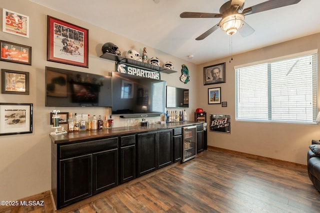 bar with wine cooler, a bar, baseboards, dark wood-style flooring, and ceiling fan