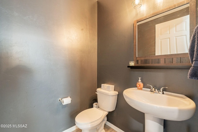 bathroom with toilet, baseboards, and a sink