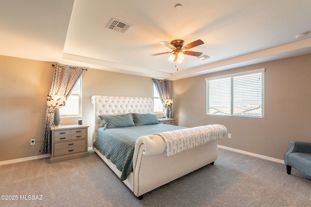 bedroom with light carpet, a raised ceiling, baseboards, and visible vents