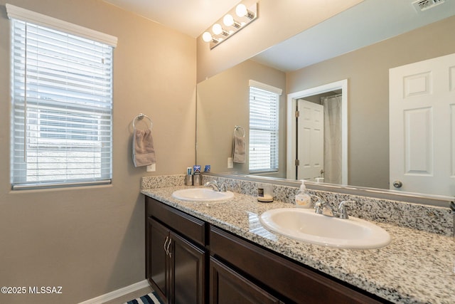 bathroom with double vanity, visible vents, baseboards, and a sink