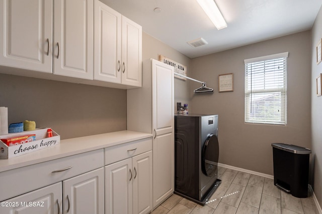 washroom featuring cabinet space, wood tiled floor, visible vents, baseboards, and washer / clothes dryer