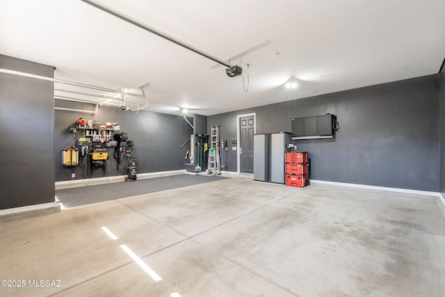 garage featuring baseboards and freestanding refrigerator