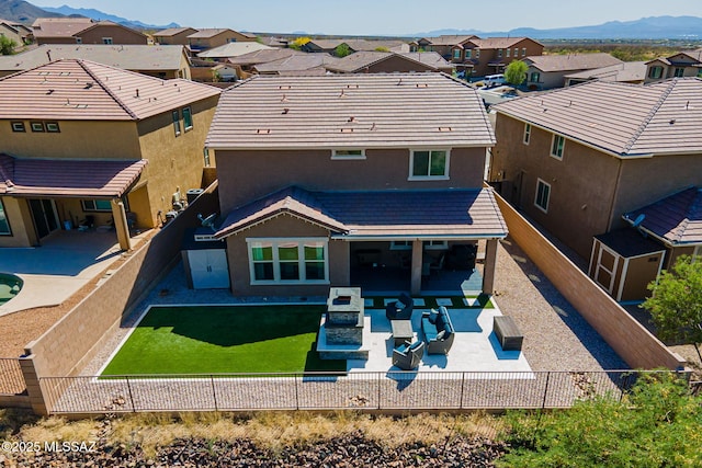 rear view of house featuring a mountain view, a residential view, stucco siding, a fenced backyard, and a patio area
