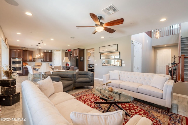 living area with recessed lighting, visible vents, light wood finished floors, and stairs