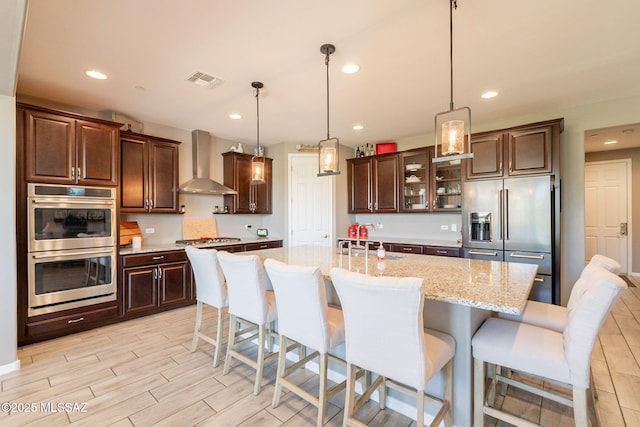 kitchen featuring stainless steel appliances, visible vents, recessed lighting, wall chimney exhaust hood, and dark brown cabinets