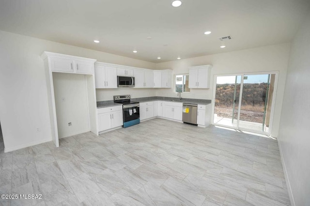kitchen with baseboards, recessed lighting, white cabinetry, a sink, and stainless steel appliances
