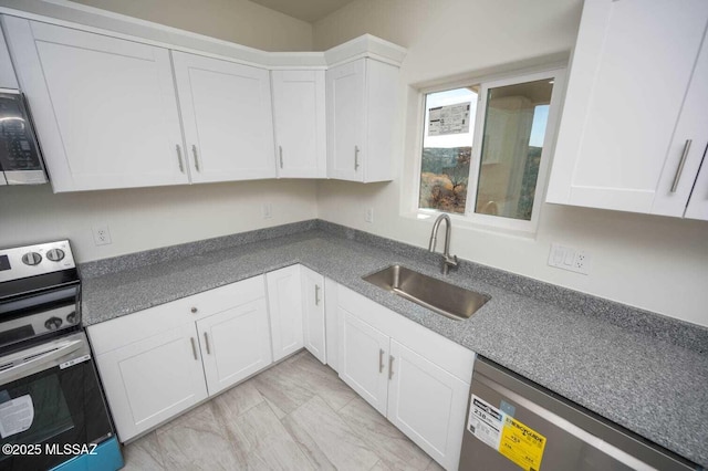 kitchen featuring marble finish floor, dark countertops, white cabinets, a sink, and stainless steel appliances