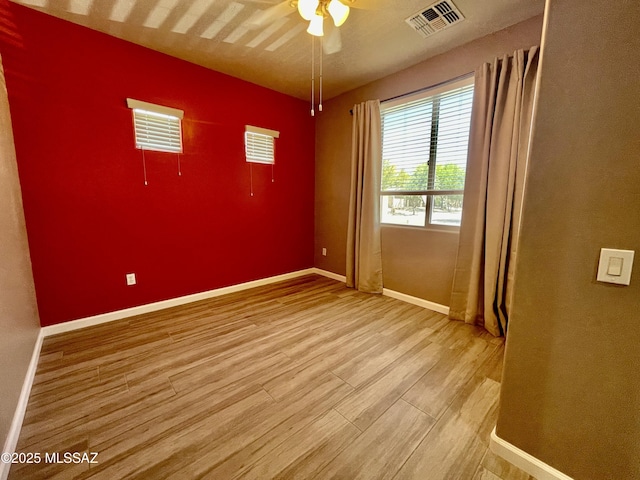 unfurnished room featuring a ceiling fan, baseboards, light wood-type flooring, and visible vents