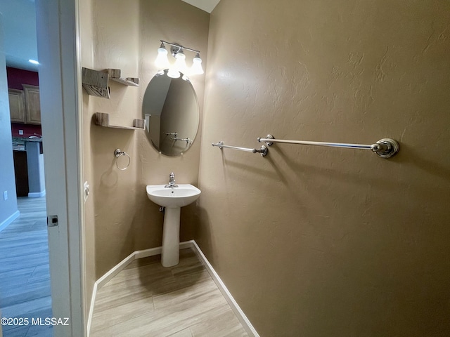 bathroom featuring wood finished floors, baseboards, and a sink