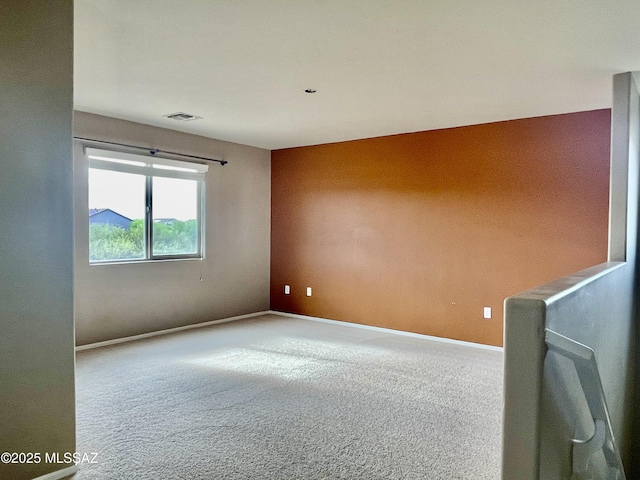 empty room featuring carpet floors, baseboards, and visible vents