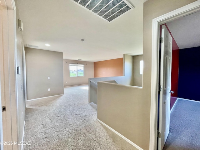hallway featuring carpet flooring, visible vents, an upstairs landing, and baseboards