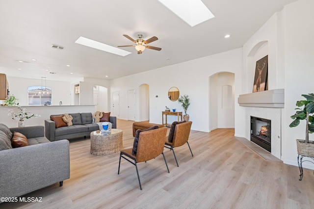 9896 E Wind Dancer Dr, Tucson, AZ 85748 - living area with a glass covered fireplace, ceiling fan, light wood-type flooring, arched walkways, and a skylight