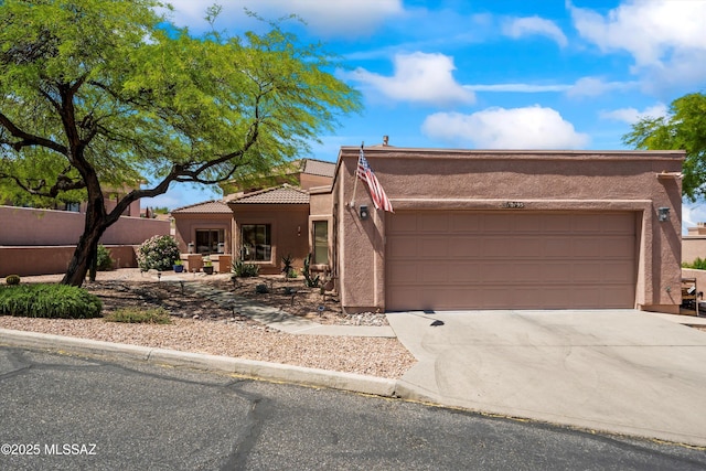 pueblo-style house with driveway, a tile roof, a garage, fence, and stucco siding