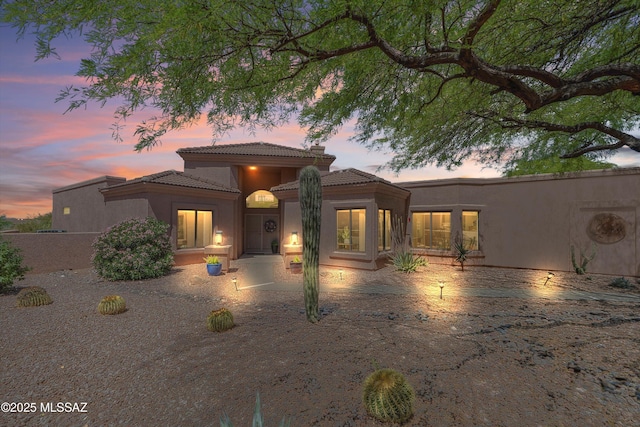 view of front of home with fence, a patio, stucco siding, and a tile roof