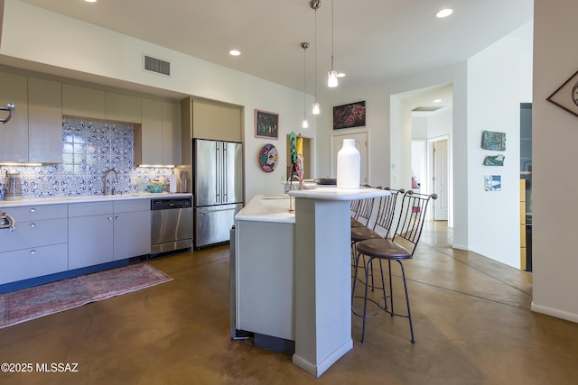4519 N Camino Kino, Tucson, AZ 85718 - kitchen featuring stainless steel appliances, gray cabinetry, decorative backsplash, finished concrete flooring, and a kitchen island with sink