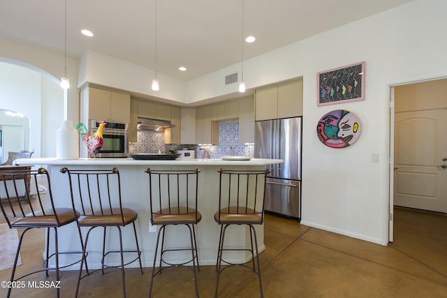 4519 N Camino Kino, Tucson, AZ 85718 - kitchen with stainless steel appliances, a breakfast bar area, concrete floors, backsplash, and under cabinet range hood