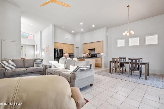 living room with visible vents, light tile patterned flooring, high vaulted ceiling, recessed lighting, and ceiling fan with notable chandelier