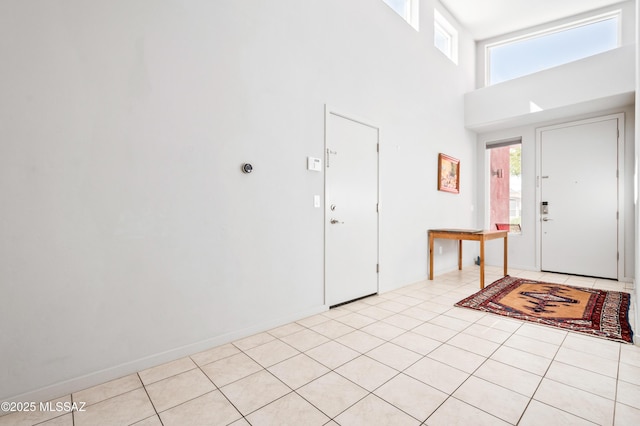 foyer featuring a towering ceiling, light tile patterned floors, and a wealth of natural light