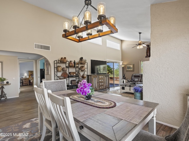 dining room featuring baseboards, a high ceiling, visible vents, and wood finished floors