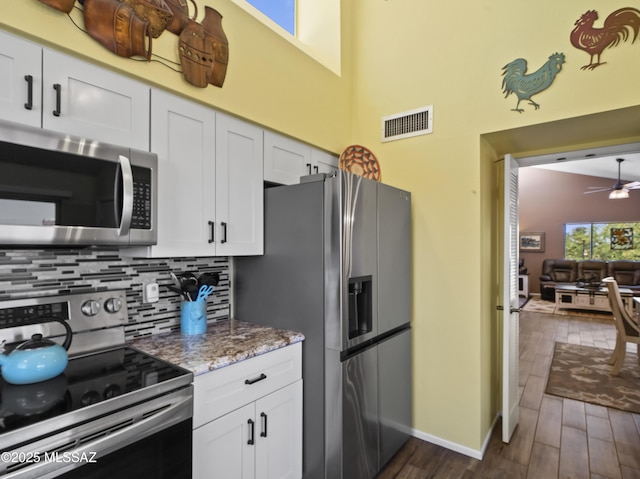 kitchen featuring backsplash, visible vents, white cabinets, dark wood-style floors, and stainless steel appliances