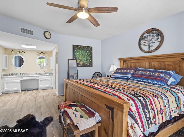 bedroom featuring visible vents, a sink, light wood finished floors, and a ceiling fan