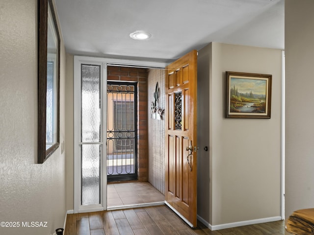 foyer entrance featuring baseboards, plenty of natural light, and wood finished floors
