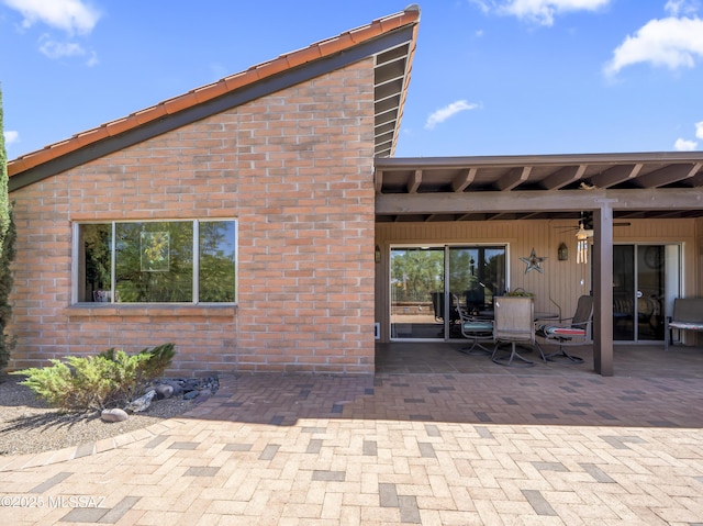 rear view of house featuring brick siding and a patio area