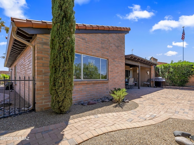 rear view of house with fence, a patio area, and brick siding