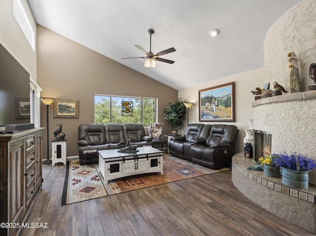 living room featuring ceiling fan, visible vents, wood finished floors, high vaulted ceiling, and a warm lit fireplace