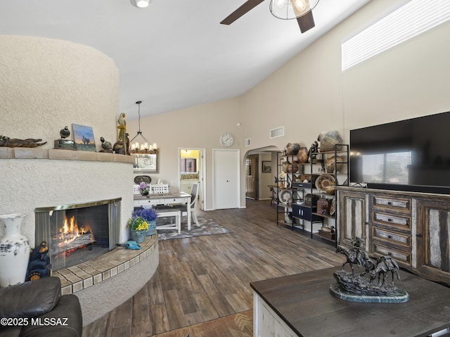 living room with visible vents, arched walkways, ceiling fan with notable chandelier, dark wood-style floors, and a glass covered fireplace