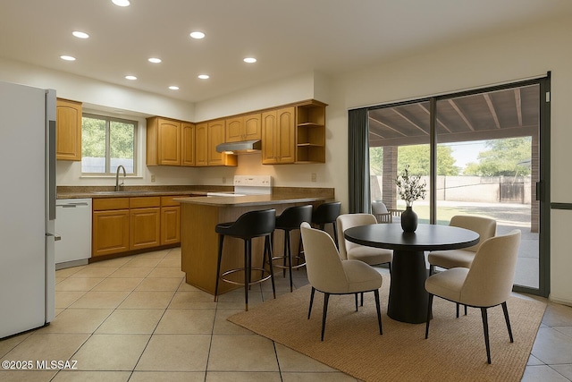 2102 E Florence Dr, Tucson, AZ 85719 - kitchen with white appliances, under cabinet range hood, recessed lighting, light tile patterned floors, and dark countertops